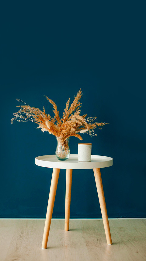 Vase with dry grass on the table on a blue background screenshot