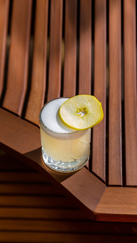 Cocktail with ice, apple and froth in a glass on the table screenshot