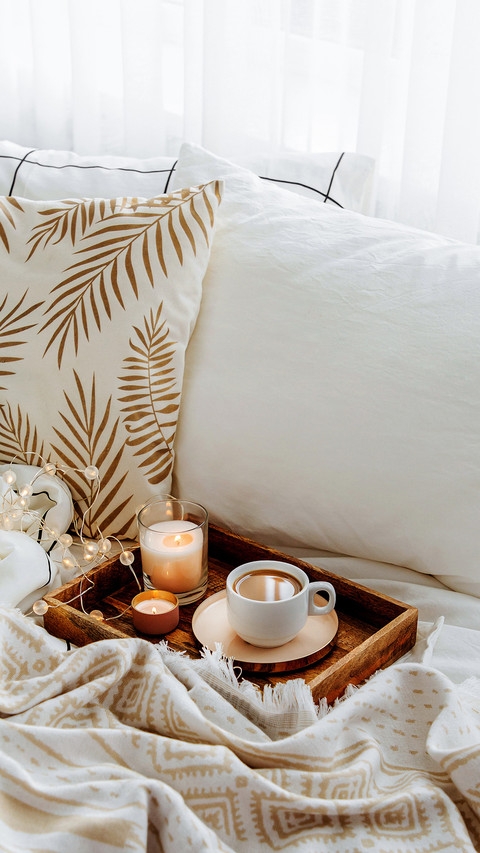 Wooden tray of coffee and candles on bed screenshot