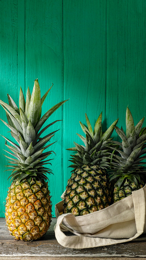 Fresh tropical pineapple standing next to more pineapples screenshot