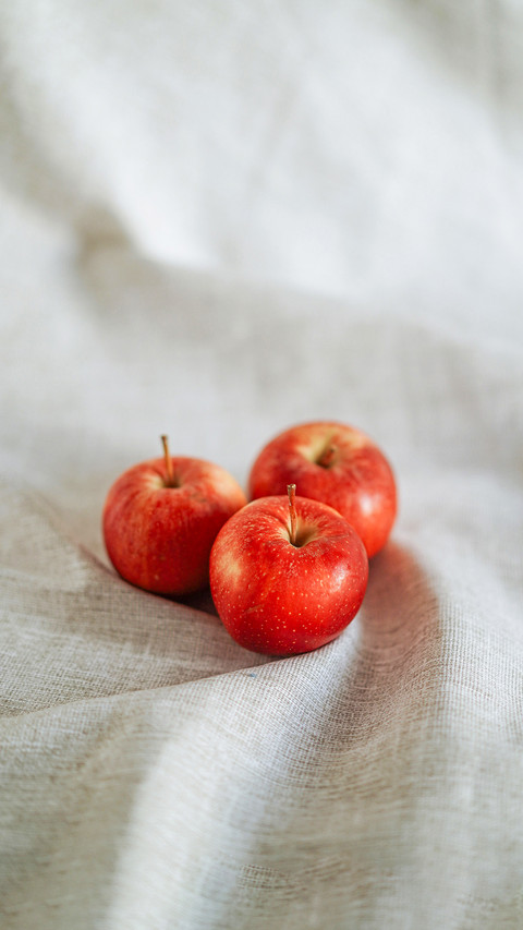 Three red apples on grey linen cloth screenshot