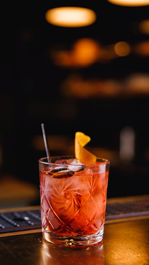 A bright orange cocktail in a transparent glass with ice screenshot