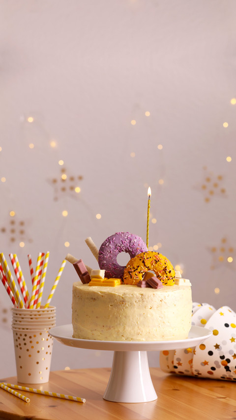 Delicious cake decorated with sweets and burning candle screenshot