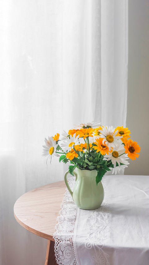 Garden daisies in a ceramic jug on a round wooden table screenshot